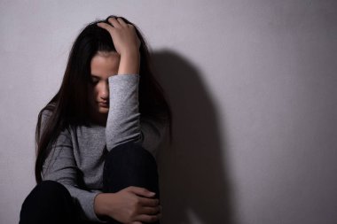 sad woman hug her knee and cry. Sad woman sitting alone in a emp