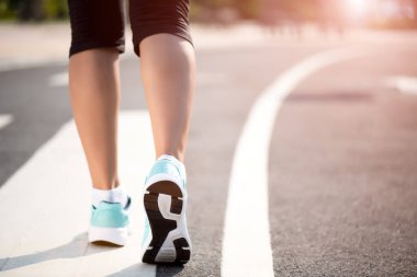 Yol tarafına doğru yürüyen bir kadın. Adım, yürüyüş ve açık hava egzersizler konsepti.