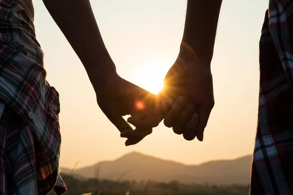 背景にある牧草地の山で日の出の夕日を歩いている間 愛するカップルの手を握って閉じます バレンタインデーと愛のコンセプト — ストック写真