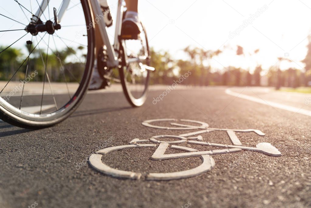 Close up cycling logo image on road with athletic women cyclist legs riding Mountain Bike in background at the morning.