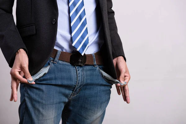 A young businessman in a business suit showing his empty pockets. Financial difficulties, bad economy, no money concept.