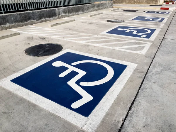 International handicapped (wheelchair) or Disabled parking symbol painted in bright blue on parking space.