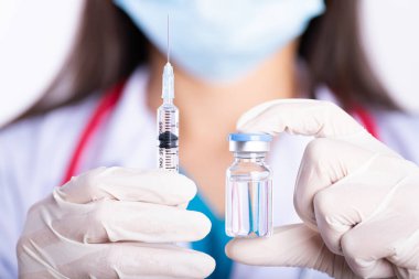 Omzunda steteskop olan kadın doktor şırınga ve aşı tutuyor. Sağlık ve Tıp Konsepti.