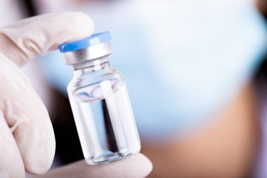 Omzunda steteskop olan kadın doktor şırınga ve aşı tutuyor. Sağlık ve Tıp Konsepti.