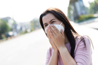 Koruyucu yüz maskesi takan ve öksüren bir kadının etrafını sarın. Coronavirus ve 2.5..
