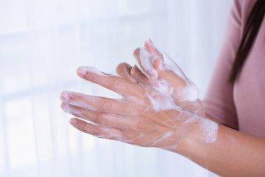 Coronavirus hastalığını önlemek için beyaz arka planda sabunla ellerini yıkayan kadın (COVID-19). Sağlık ve dezenfeksiyon konsepti.