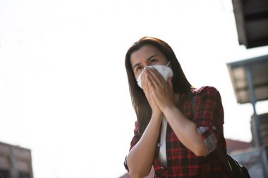 Koruyucu yüz maskesi takan ve öksüren bir kadının etrafını sarın. Coronavirus ve 2.5..
