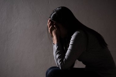 Üzgün kadın yüzünü kapat ve ağla. Karanlık bir odada yalnız oturan üzgün kadın..