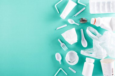 Yeşil pastel arka planda farklı çöp maddelerinin üst görüntüsü. Geri dönüşüm, Dünya Çevre Günü, yeşile dön ve çevre kavramı