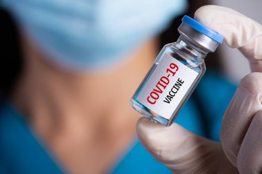 Omzunda steteskop olan kadın doktor şırınga ve COVID-19 aşısı. Sağlık ve Tıp Konsepti.