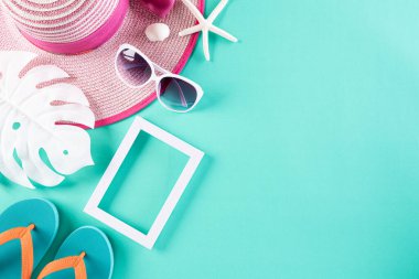 Plaj aksesuarları terlik, güneş gözlüğü, denizyıldızı, plaj şapkası ve deniz kabuğu yaz tatili ve tatil konsepti için yeşil pastel arka planda..