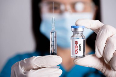 Omzunda steteskop olan kadın doktor şırınga ve COVID-19 aşısı. Sağlık ve Tıp Konsepti.