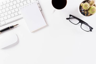 Üst kattaki ofis masasında yatıyordu. Klavyeli çalışma alanı, ofis malzemeleri, beyaz arkaplanda kopya alanı olan kalem ve kahve fincanı.