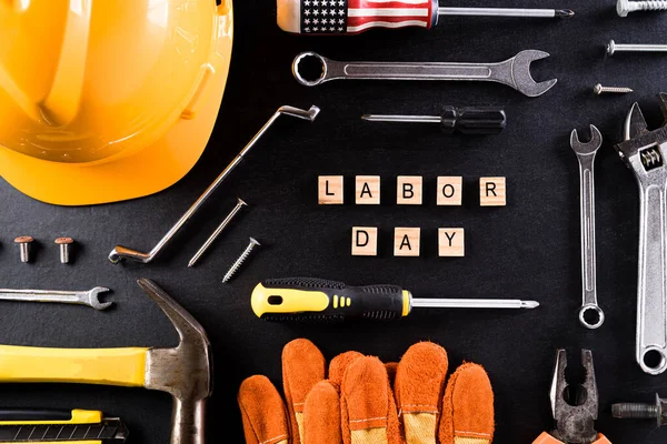 Happy Labor day concept. Different construction tools on black table background, with Labor Day text.