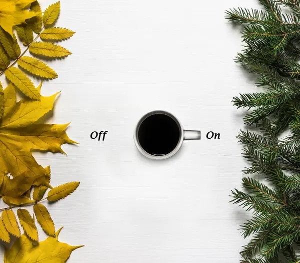 Eine Tasse Kaffee auf einem weißen Tisch symbolisiert den Beginn des Winters und das Ende des Herbstes sieht aus wie ein Schalter in Position auf — Stockfoto