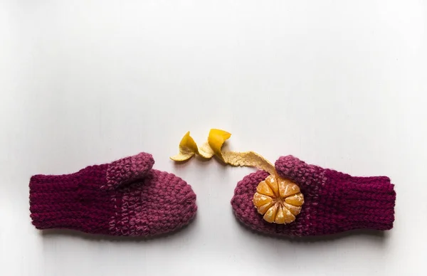 stock image on white table mittens with mandarin orange on palm peeled peel