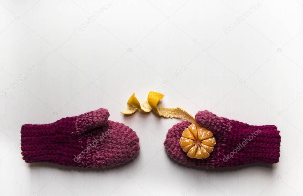 on white table mittens with mandarin orange on palm peeled peel