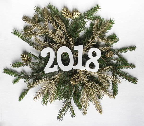 Sur une couronne de branches de sapin et de brindilles dorées et de cônes se trouve le nombre de vacances du Nouvel An 2018 — Photo