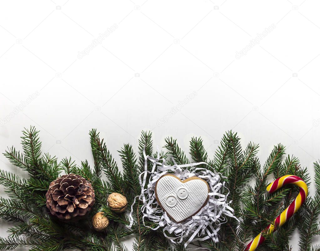 on a white background on the spruce branches lying on a Christmas gingerbread walnuts cone and lollipop caramel candy staff Santa Claus