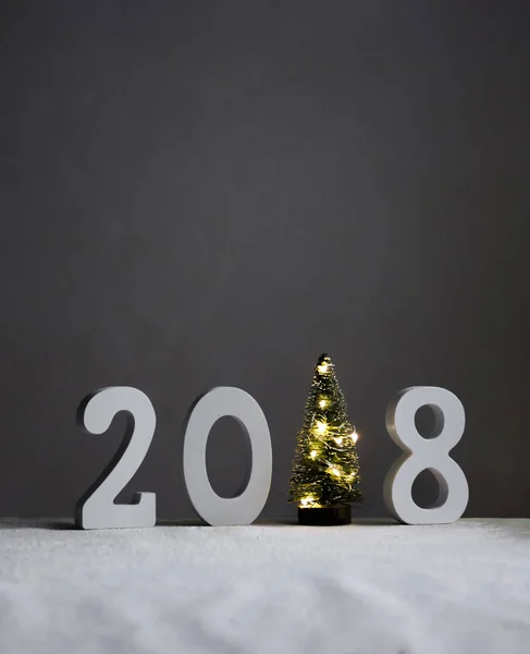 Sur le terrain enneigé, il y a des chiffres 2018 au lieu d'une seule pièce feux sapin lueur — Photo