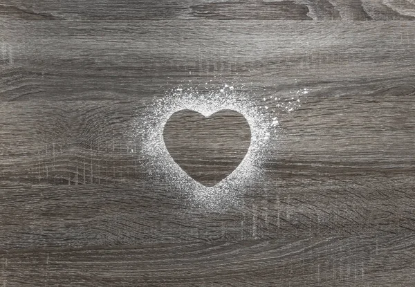 Op een houten achtergrond met gemalen poeder sneeuw een silhouet van het hart — Stockfoto