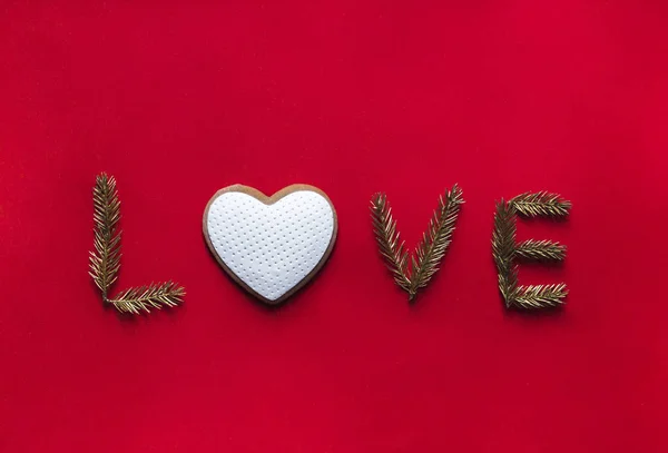 Op een rode achtergrond het woord liefde in plaats van letters over cookies in de vorm van een hart — Stockfoto