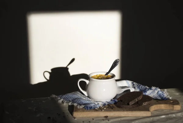 På tabell blå servetten med prydnad mönster och soppa terrin med gul soppa på solen bröd träskiva frön mörk bakgrund — Stockfoto
