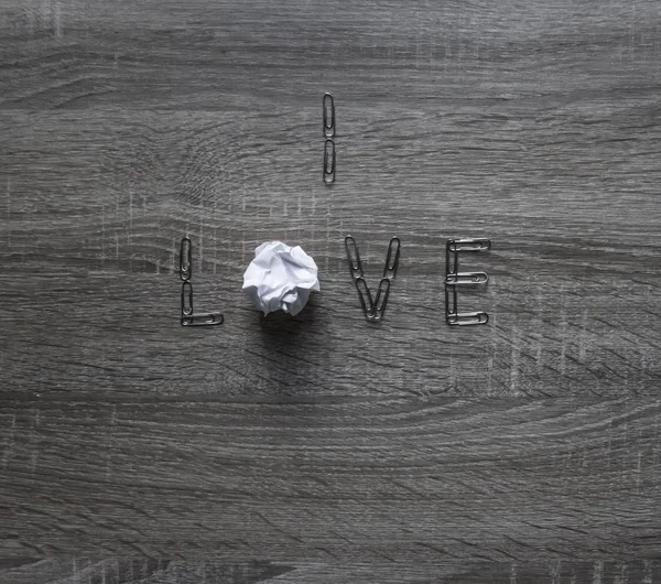 Op de houten achtergrond is een clip van de liefde, in plaats van de letters o per stuk papier munt — Stockfoto