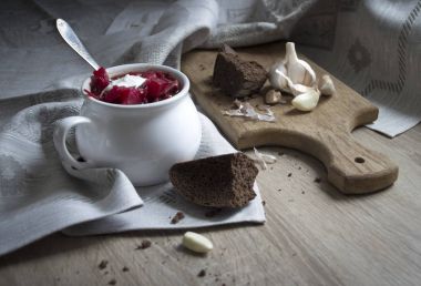 masada kırmızı pancar çorbası üzerinde güneş ekmek sarımsak ekşi krema ile süsleme desen ve çorba kasesi ile mavi peçete 