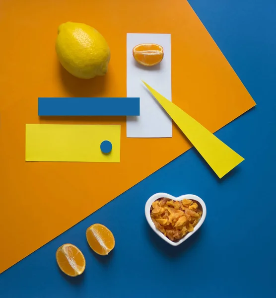 Naranja limón sobre un fondo brillante azul amarillo naranja triángulo círculo rectángulo geometría corazón frutos secos frutas confitadas — Foto de Stock