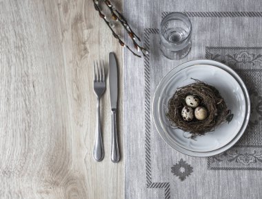 bir masaya bir tabak çatal bıçak bir willow dal bir yumurta ile bir yuva ile peçete 