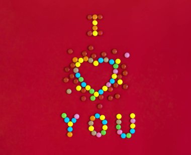 tatlılar ile yazılı kırmızı bir arka plan üzerinde renkli yuvarlak şekerler ile bir kalp şeklinde seniseviyorum 