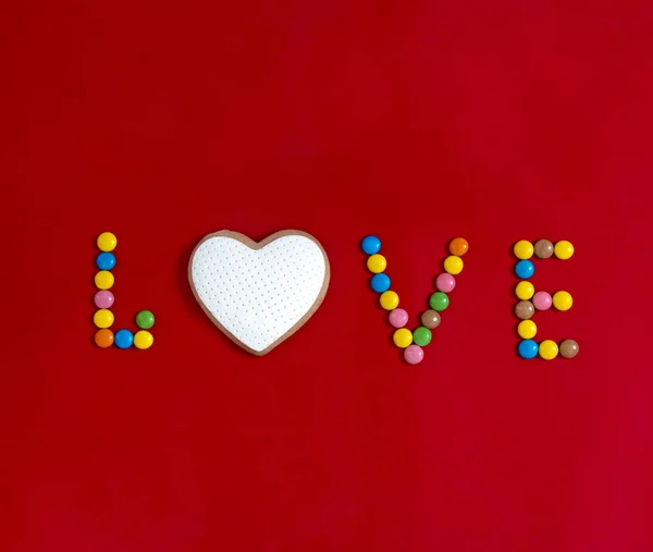 På en röd bakgrund skriven i godis som jag älskar i form av hjärta runda kakor med vitt mastix med flerfärgade godis — Stockfoto