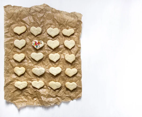 Liggen op een witte achtergrond op het Perkamentpapier voor het bakken van een cookie in de vorm van hart op een stomp formulier multi-gekleurde stokjes — Stockfoto
