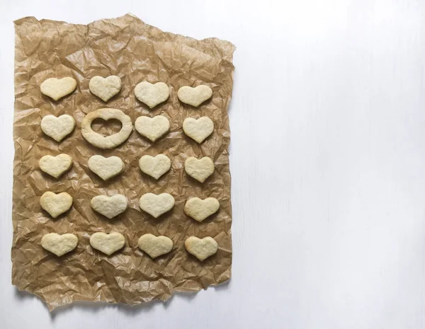 Op een witte achtergrond op papier bakken ligt een cookie in de vorm van een hart en een plaats is leeg — Stockfoto