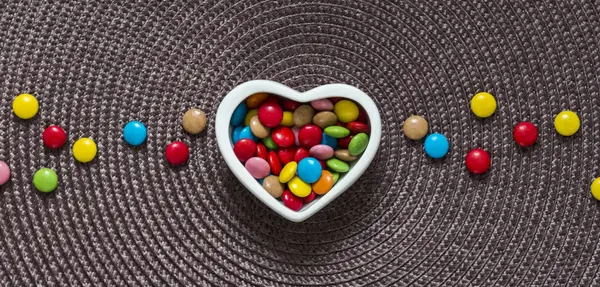 Op een servet in het midden van een vaas met gekleurde in de vorm van een hart en leugen candy candy — Stockfoto