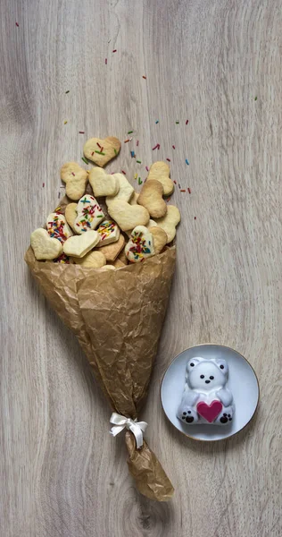 Op een houten tafel ligt een stapel van verfrommeld papier met cookies in de vorm van harten en een stapel van kleurrijke en pyrofessional souffle in de vorm van een beer met een hart — Stockfoto