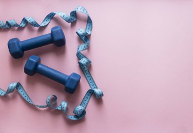 bir pembe arka plan dumbbells mavi ve uçan santimetre şekil spor yumuşak ışık 