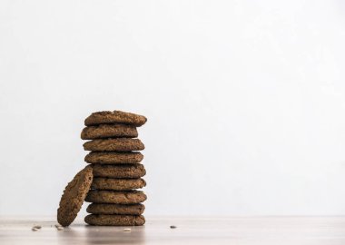 Beyaz bir arka plan üzerinde ahşap bir masa üzerinde Ayçekirdeği yulaf ezmeli kurabiye yığını duruyor 