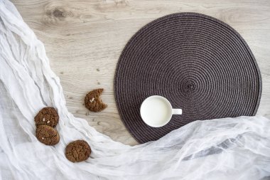 Beyaz ve koyu yuvarlak peçete yalan yulaf ezmesi üzerinde ahşap bir masa üzerinde bir bardak süt kırıntıları çerezleri Ayçiçeği tohumları tezcan 