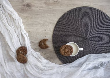 Beyaz ve koyu yuvarlak peçete yalan yulaf ezmesi üzerinde ahşap bir masa üzerinde bir bardak süt kırıntıları çerezleri Ayçiçeği tohumları tezcan 