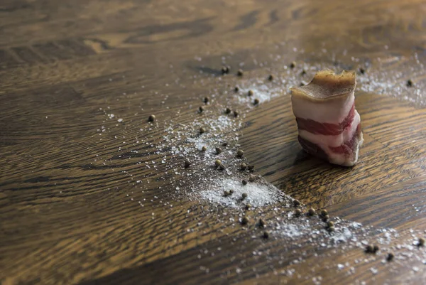 Sobre un fondo de madera de chuletas de color marrón oscuro círculo sal marina pimienta grande condimento cilantro vertido un pedazo de grasa de tocino — Foto de Stock