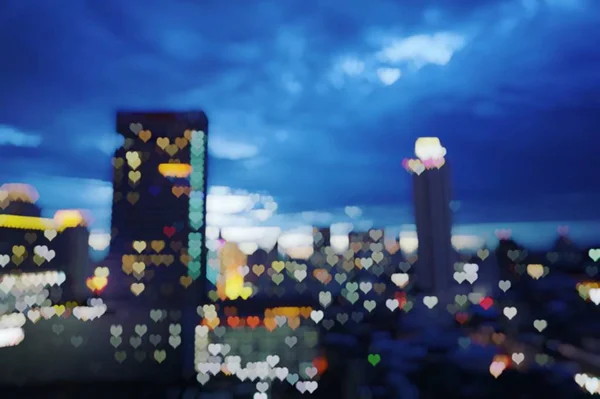 Forma de corazón bokeh luz de la ciudad raspar en el crepúsculo — Foto de Stock