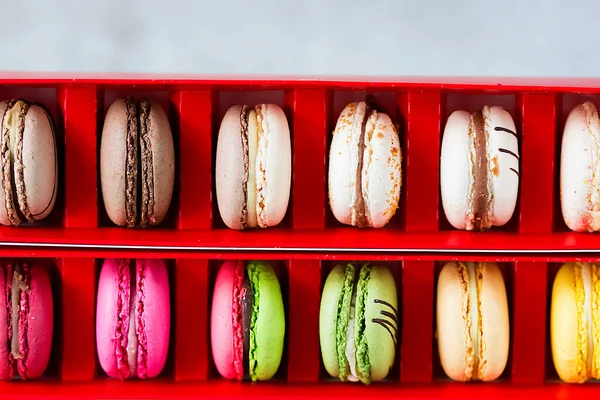 Assorted macaroon cakes in a red box  on a gray background. Soft focus.