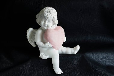 Siyah arka planda pembe kalpli beyaz bir melek. Yumuşak odak.