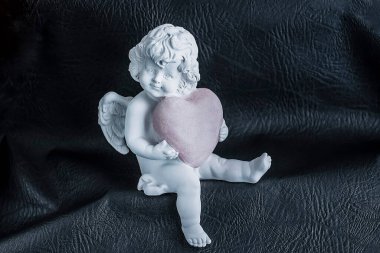 Siyah bir arka planda pembe kalpli bir melek. Yumuşak odak.