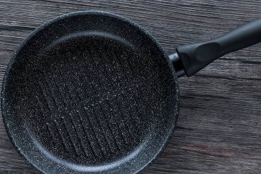 Kahverengi ahşap arka planda siyah tava. Üst görünüm.