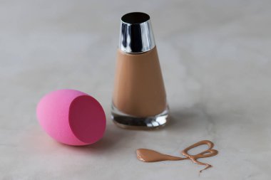 Pembe kozmetik sünger ve fondöten ve fondöten birikintisi. Yumuşak odak.