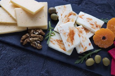 Siyah tahtada çeşit çeşit peynirler var. Siyah arka plan. Yumuşak odak.