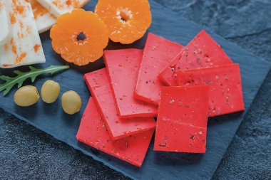 Siyah tahta üzerinde çeşitli peynirler, zeytin, ceviz ve meyveler. Yumuşak odak.